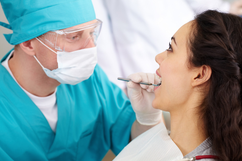 Dentist in protective glasses carrying out a dental check-up